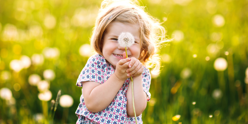 Löwenzahn-Projekt in der Kita, Mädchen mit Pusteblume