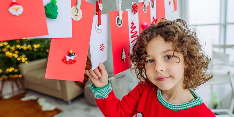 Kind vor selbstgebsteltem Adventskalender