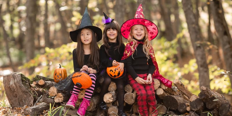 Drei Mädchen im Halloween-Kostüm Hexe sitzen im Wald