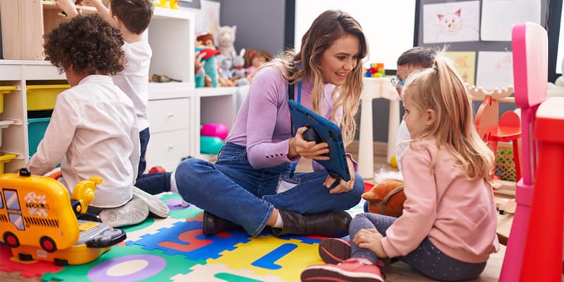 Portfolioarbeit digital: Schnell und gut? Erzieherin mit Kindern am Tablet