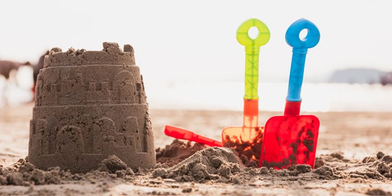 Spielen mit Sand, Matsch und Wasser, Sandburg und Schaufel am Strand