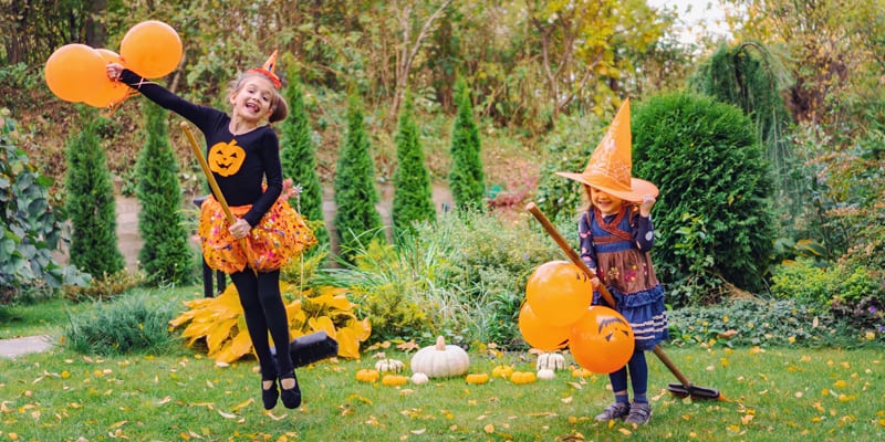 Zwei Mädchen spielen auf einem Besen Hexe